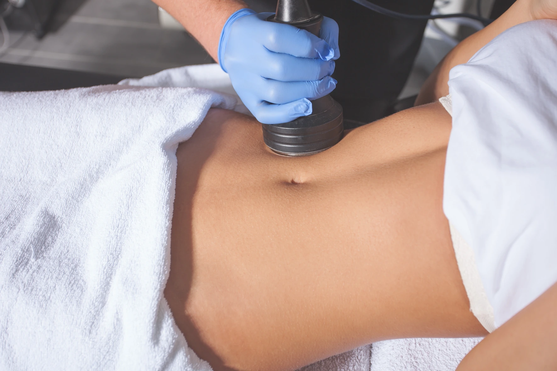 Female patient receiving CellSound body contouring treatment on her stomach.