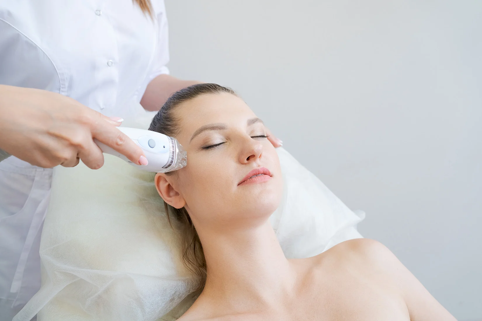Female patient receiving enlarged pores treatment on her face with a radiofrequency device.