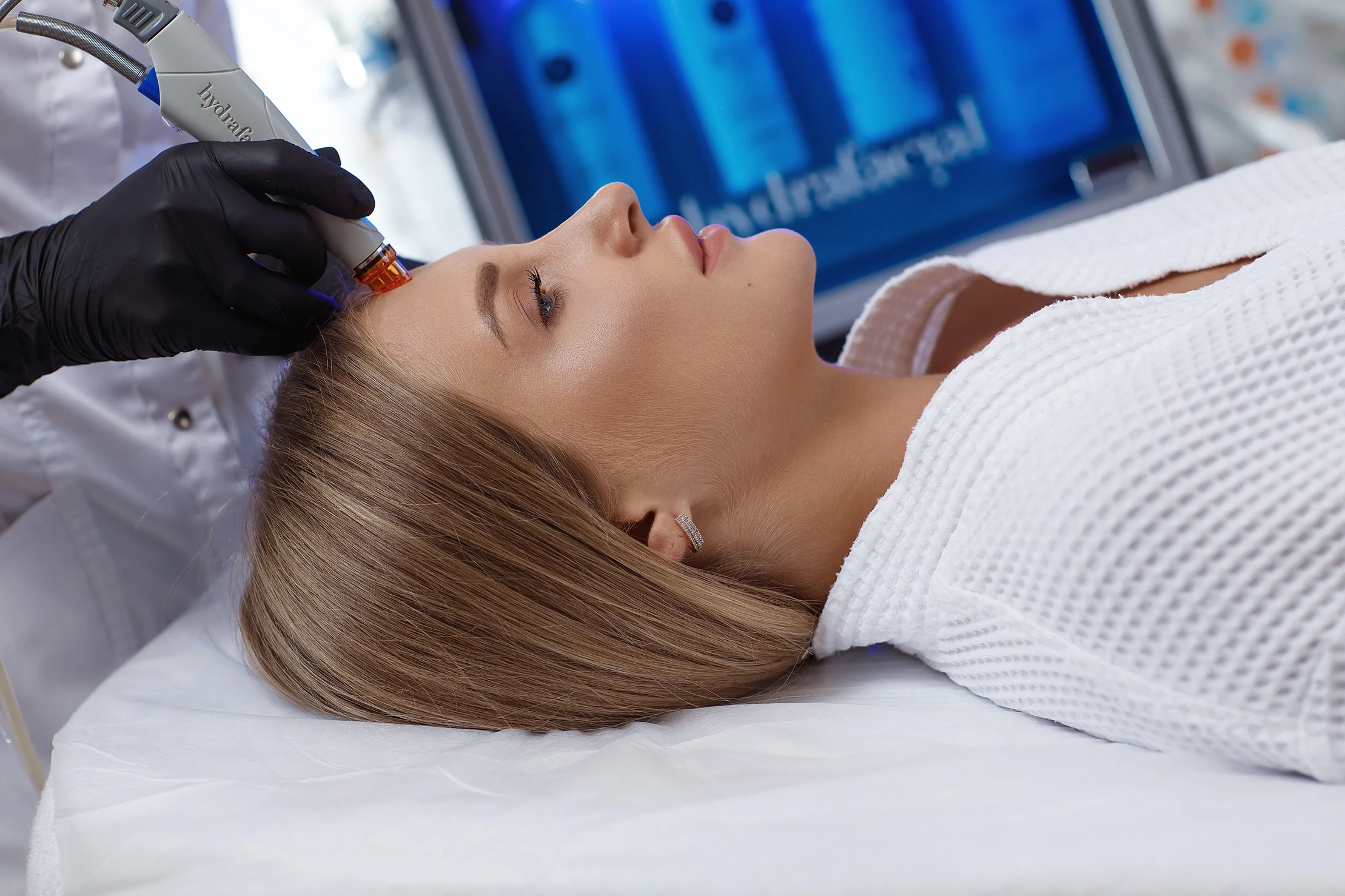 Female patient receiving facial rejuvenation treatment with a microneedling device.