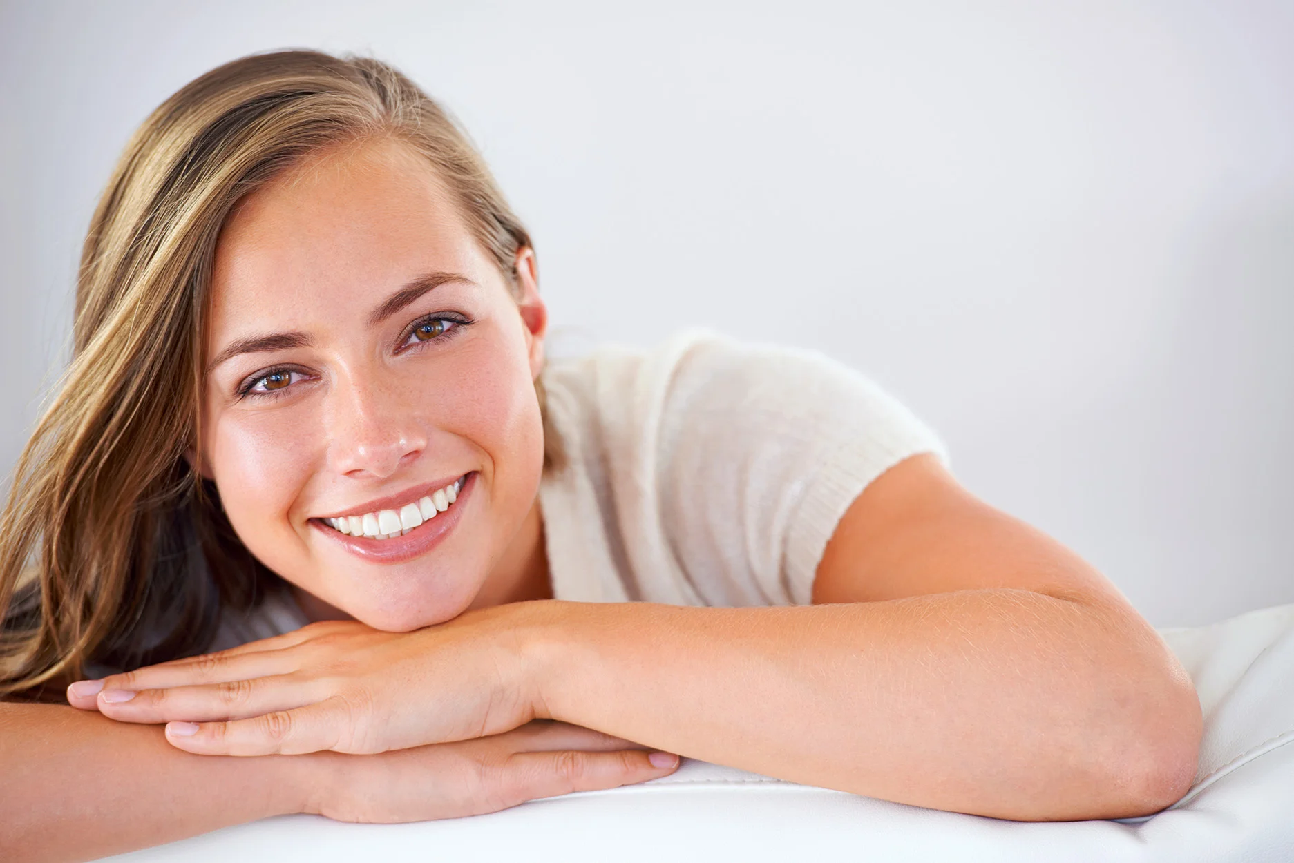 Smiling, happy woman representing confidence and wellness associated with non-invasive labial correction treatment.