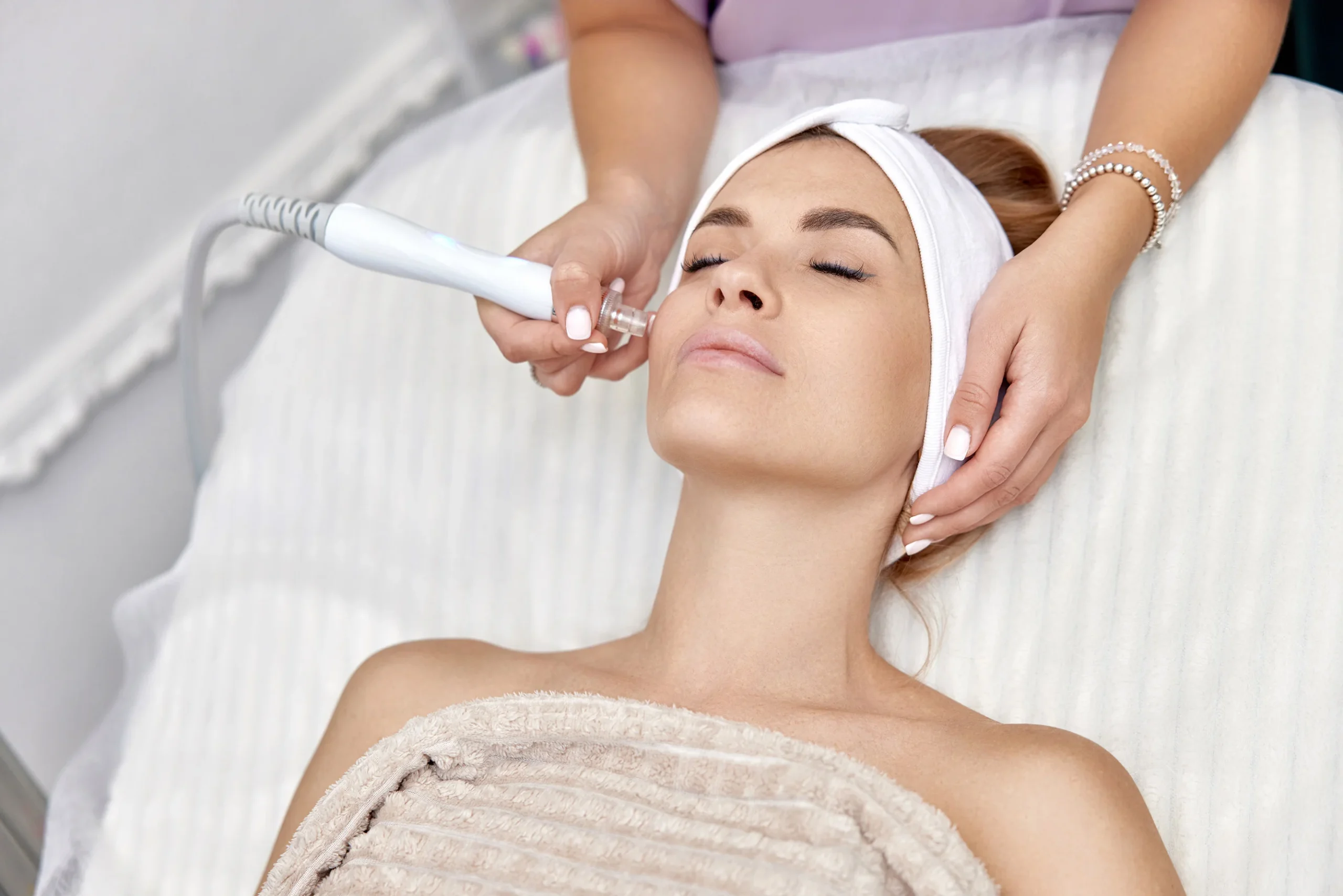 Female patient receiving scar reduction treatment on her face to improve the appearance of a facial scar.